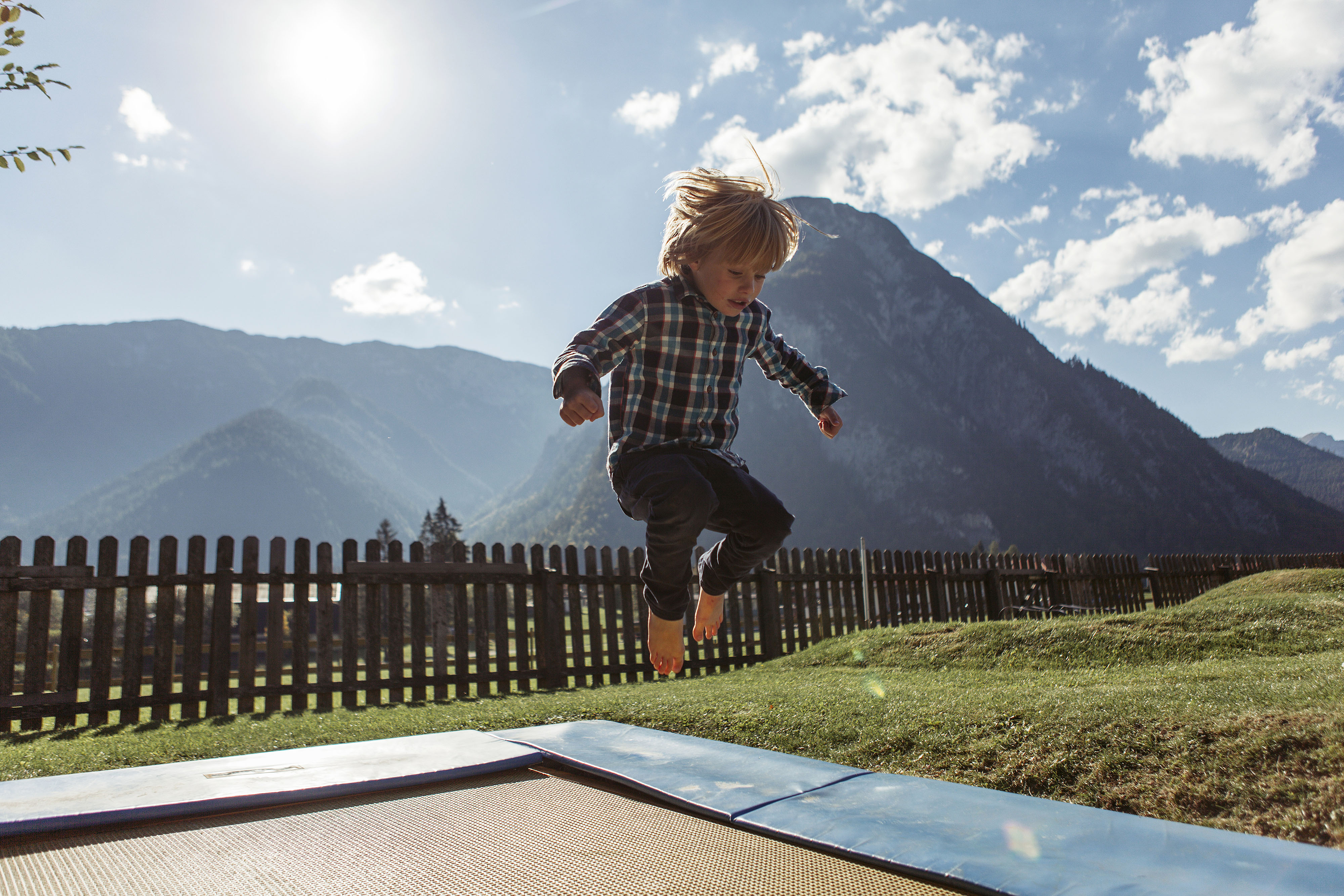 Small child jumping on a trampoline with mountains in the background