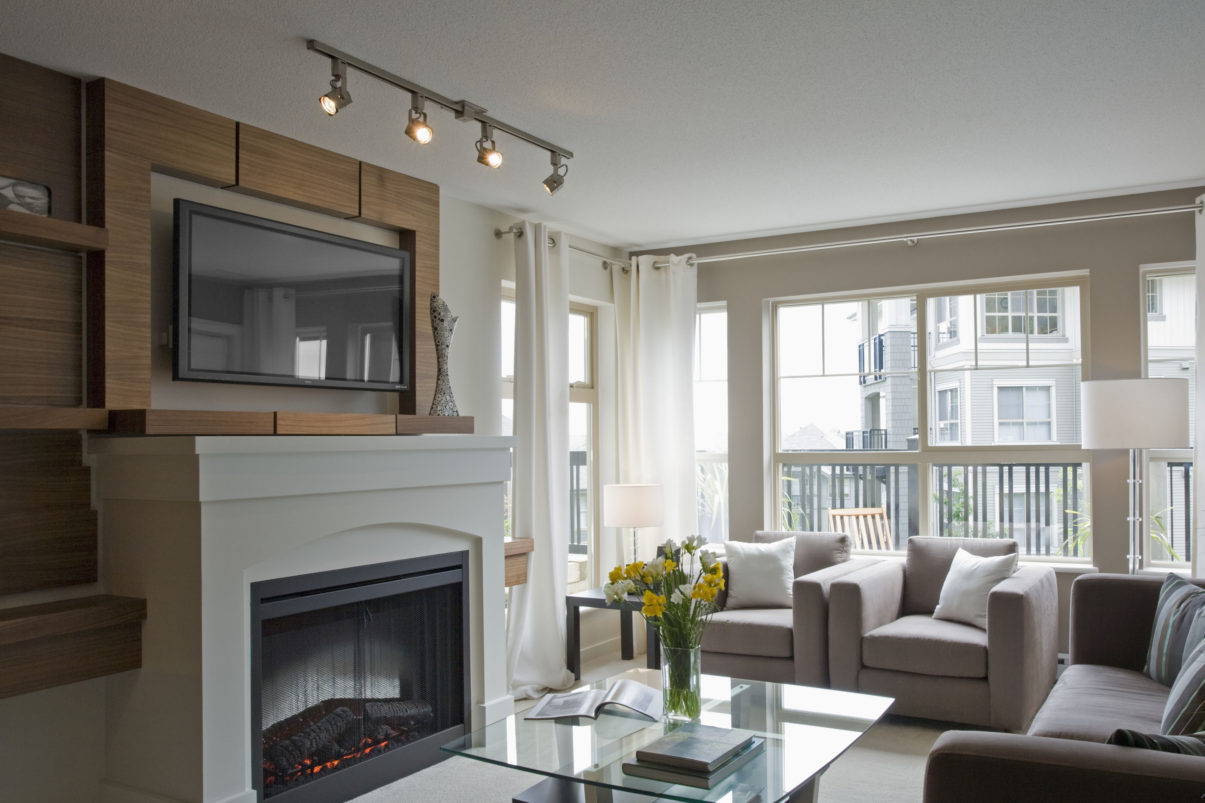 Track lighting used to emphasize tv and fireplace in a living room