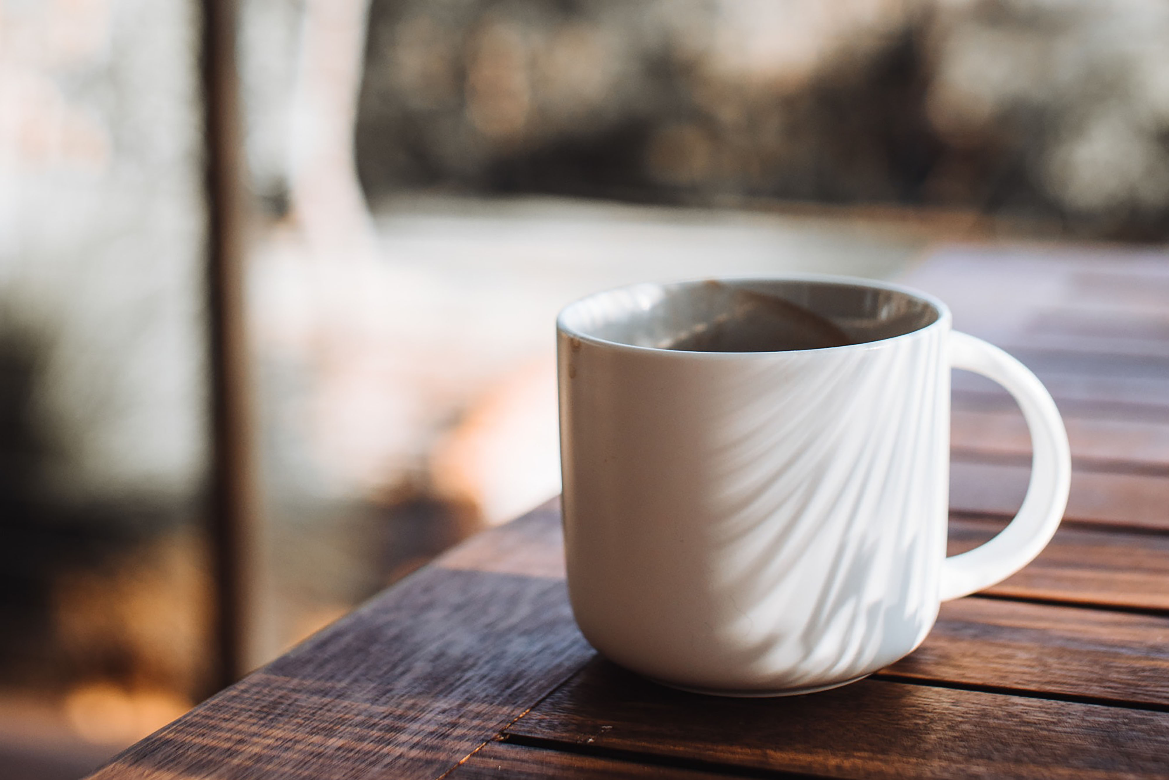 White mug full of coffee on wood table