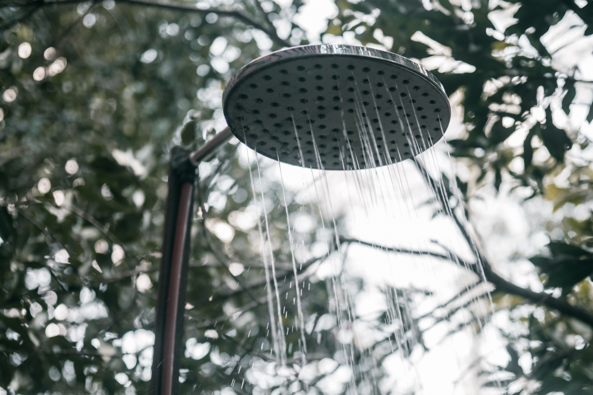 Outdoor rain shower head with trees in the background