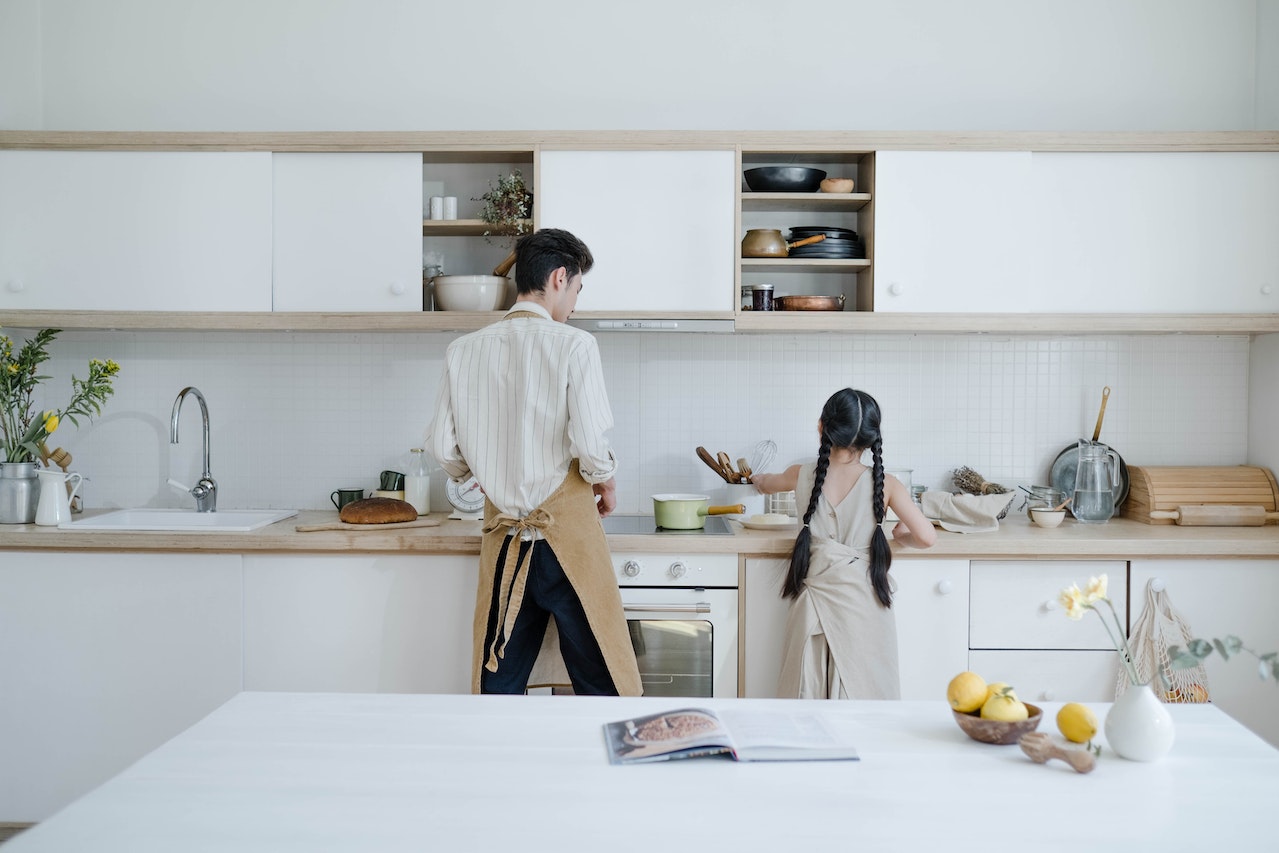 Father and daughter cooking in front of pvc kitchen cabinets