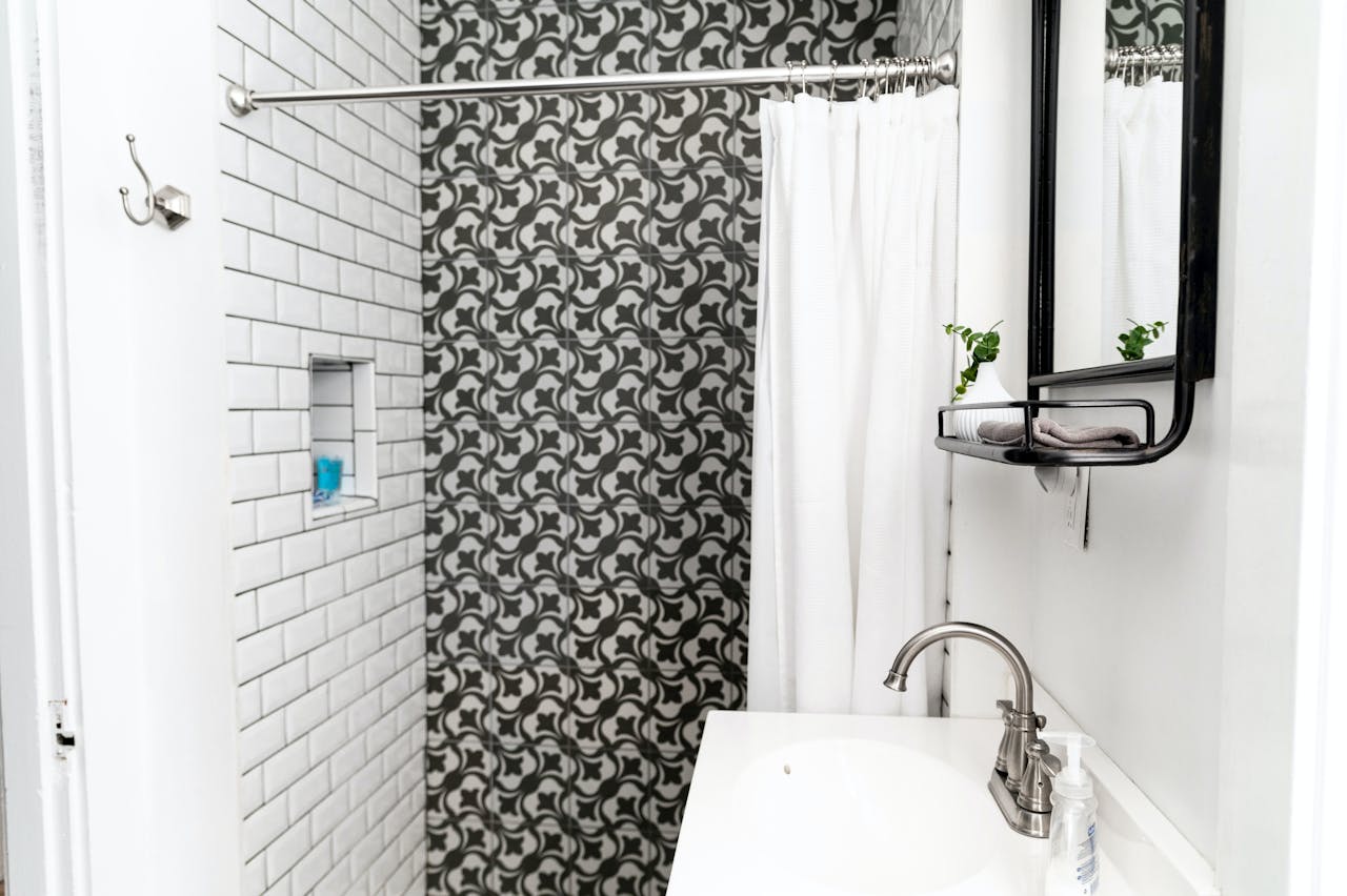 Black and white bold patterned shower with subway tiled shower niche