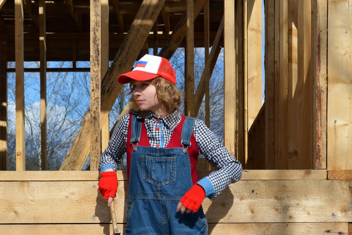 woman posing by a house stud frame being constructed