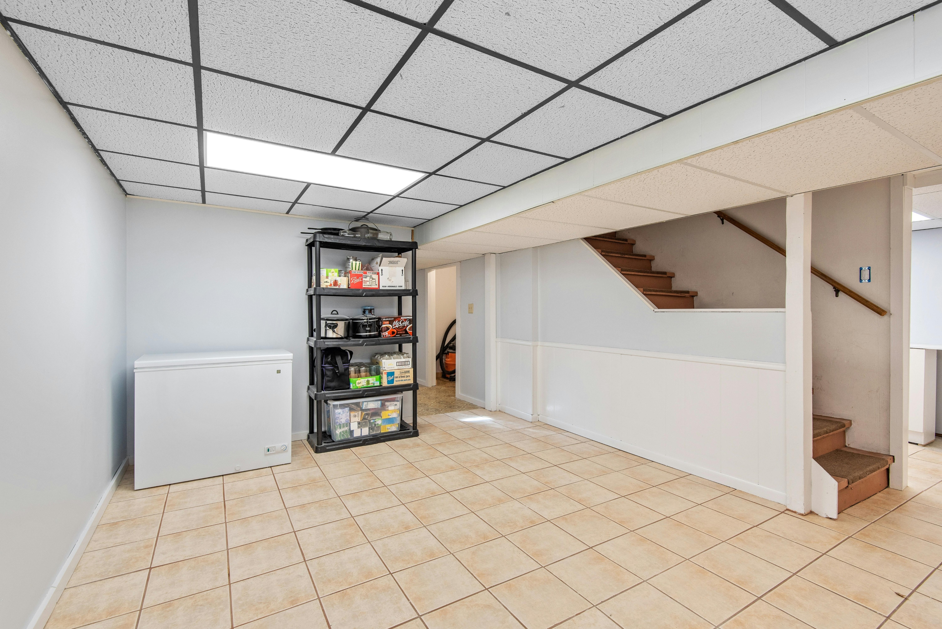 Empty basement with freezer and tiled floor