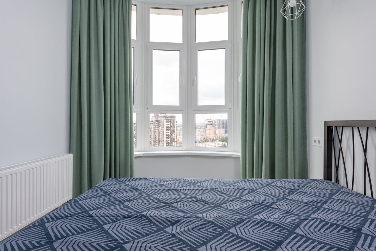 Bay window in bedroom with green curtains