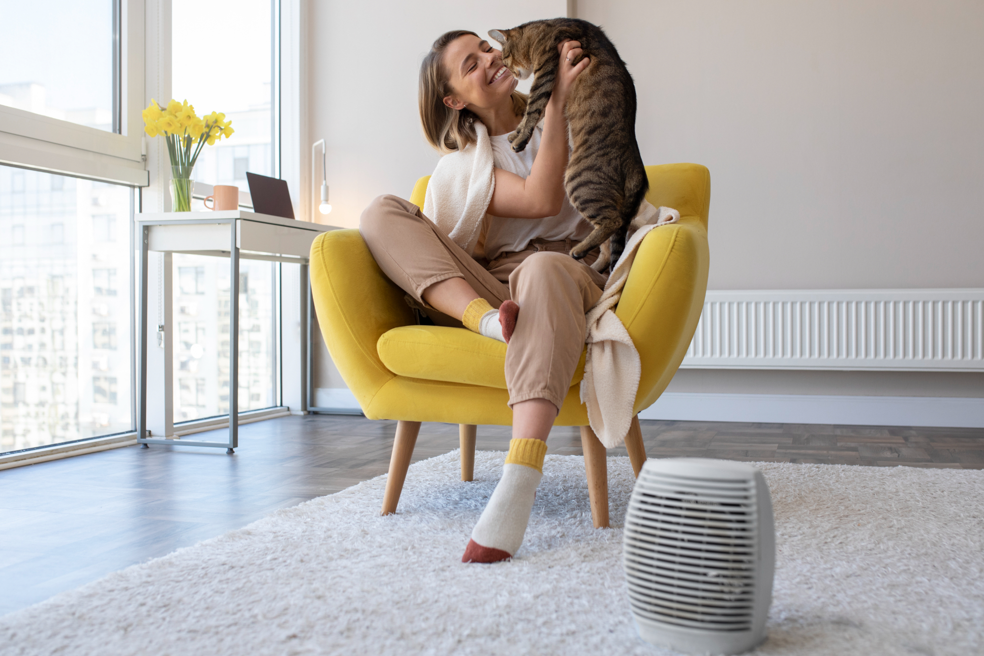 Woman sitting in yellow chair with a cat next to an air purifier