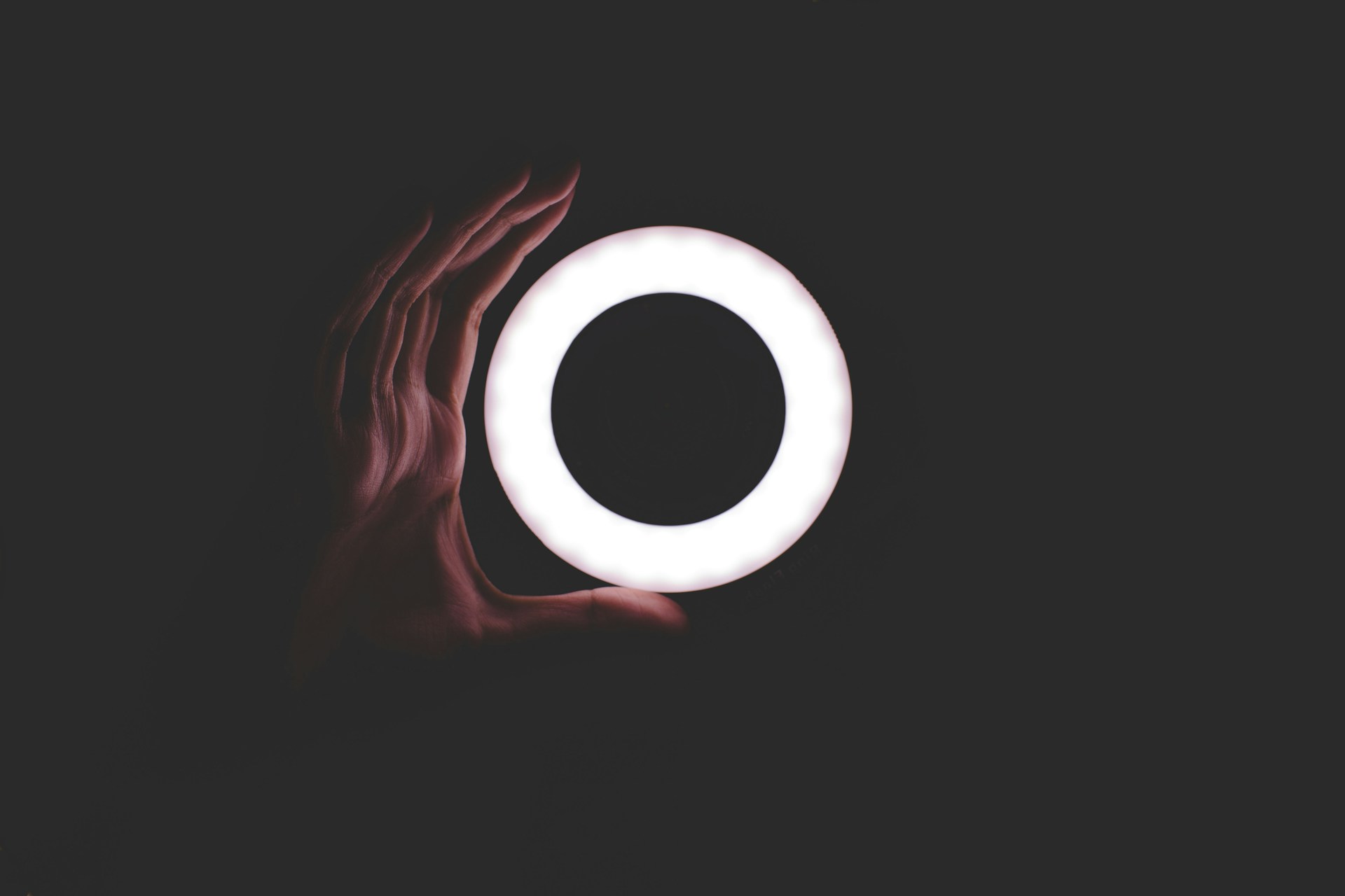 Hand in the dark holding a circle light with cool tones