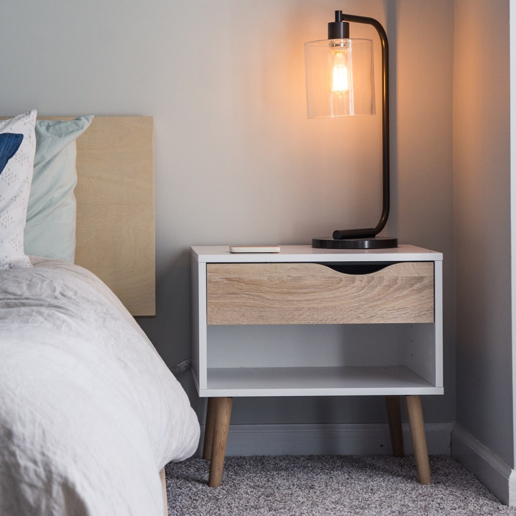 tall curved lamp on light wood bedside table