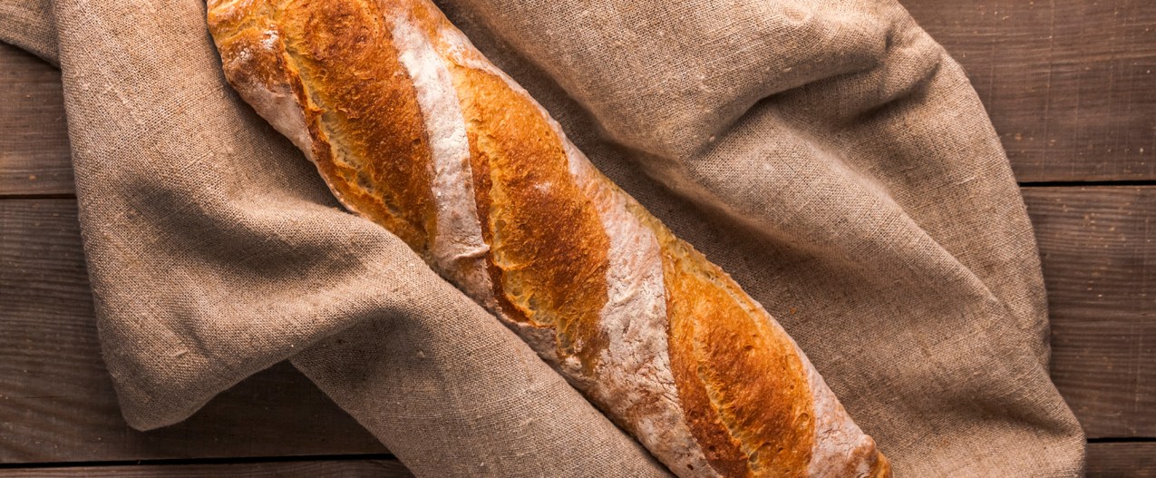 French baguette on linen bread bag on wooden counter top