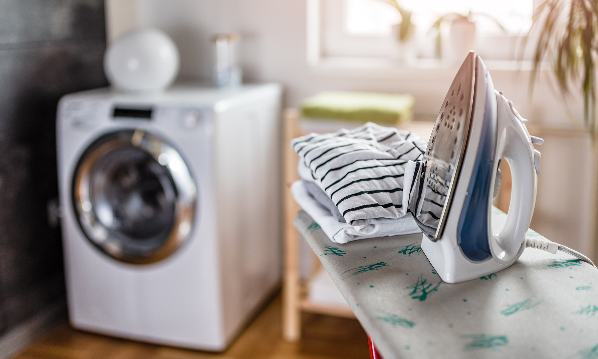 Iron and clothes on an ironing board in a laundry room