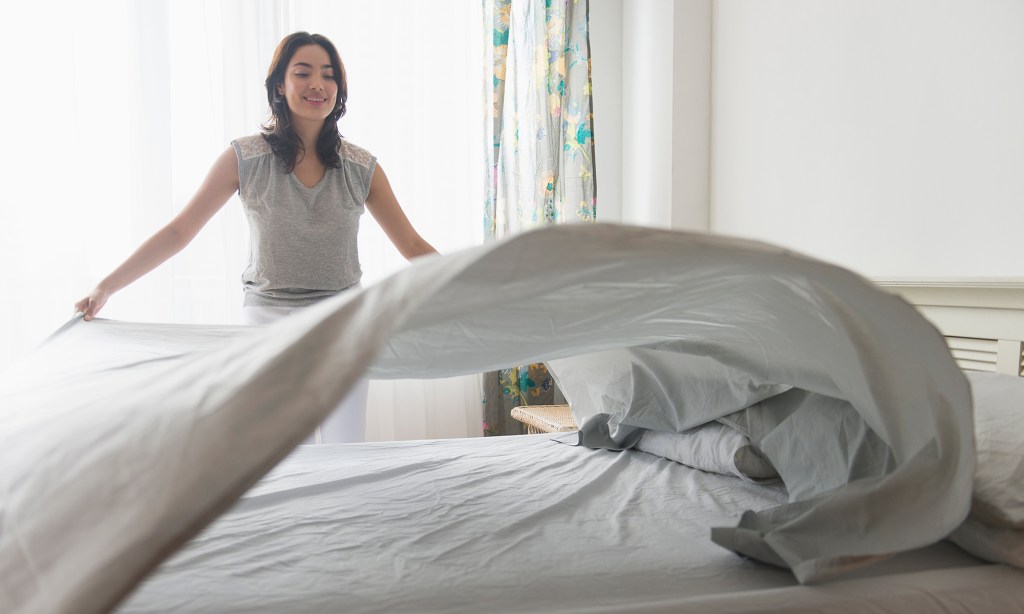 woman laying sheet flat on bed