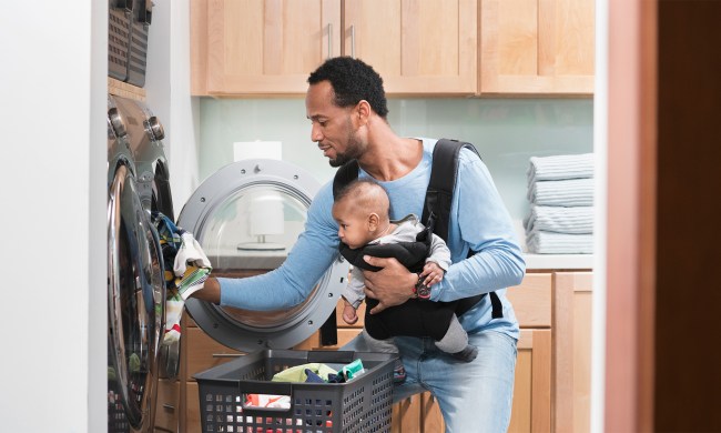 Father holding baby while doing laundry