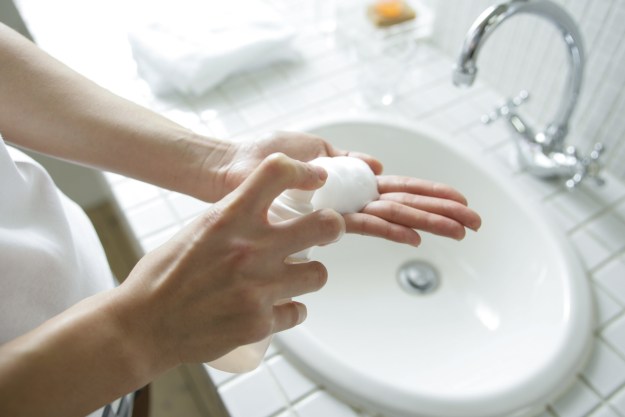 Mid section view of a person spraying soap on the palm of their hand
