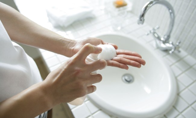 Mid section view of a person spraying soap on the palm of their hand