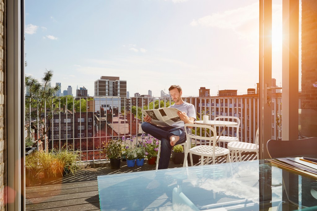 Reading the paper on an apartment deck