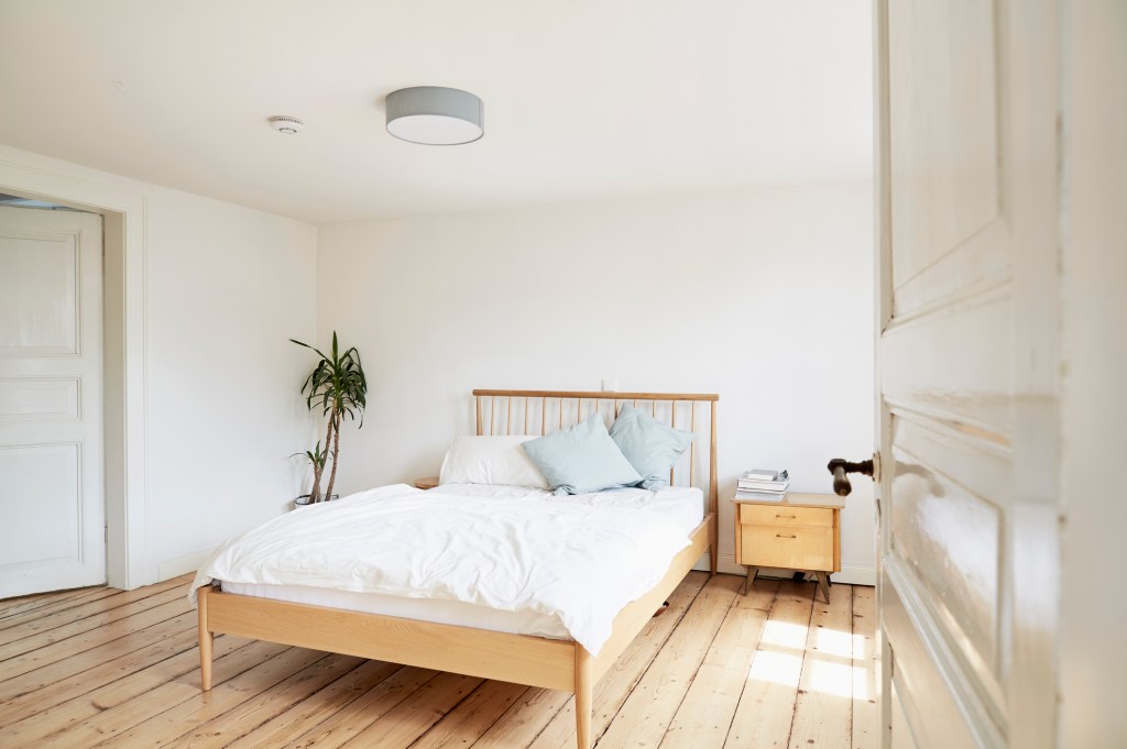 Bright modern bedroom with wood floor and white linens