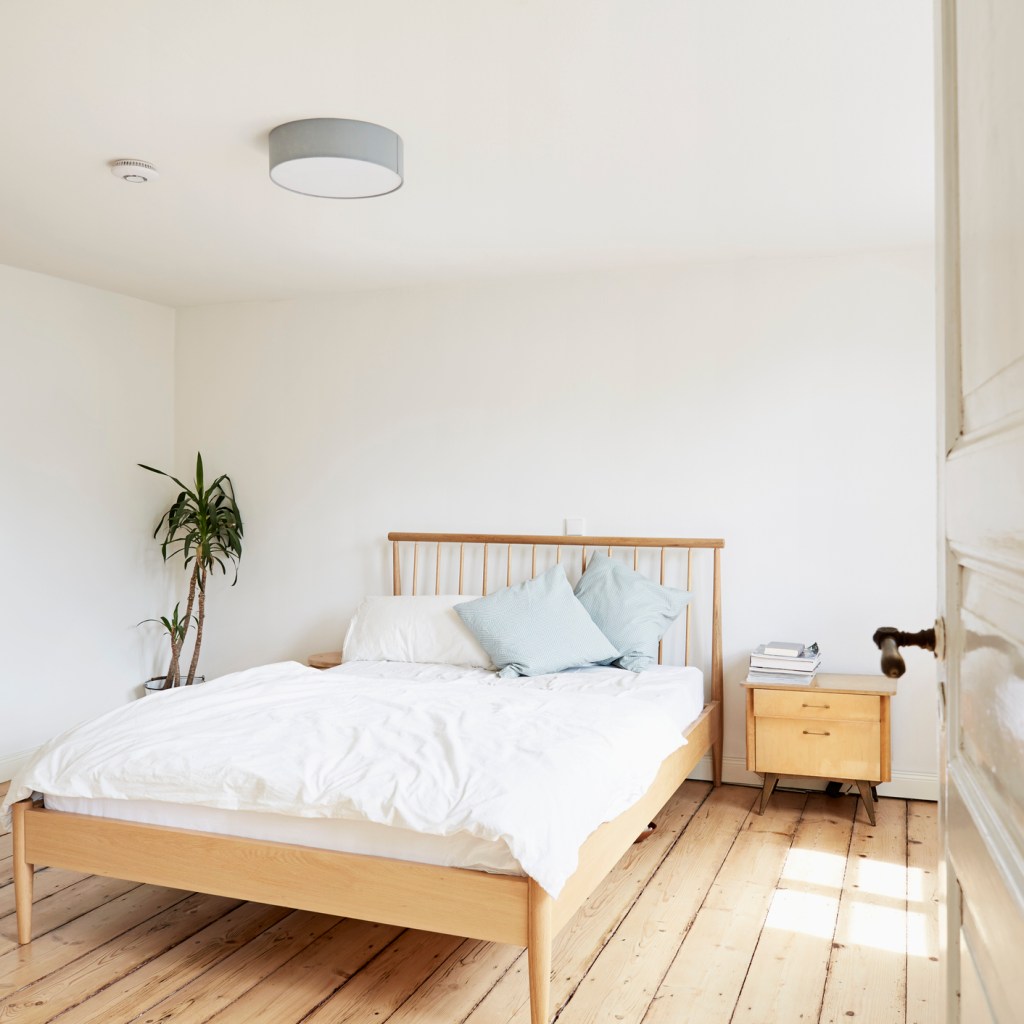 Bright modern bedroom with wood floor and white linens