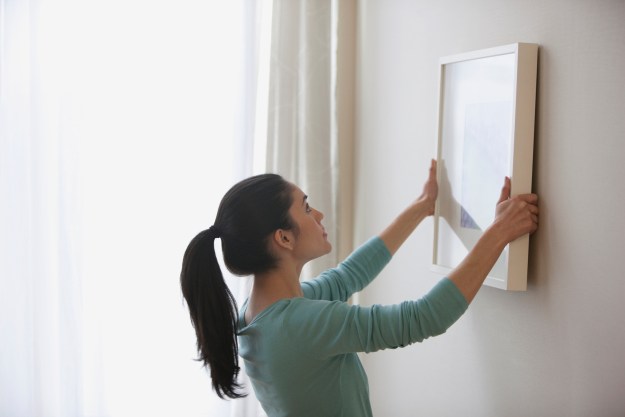 woman hanging frame on wall