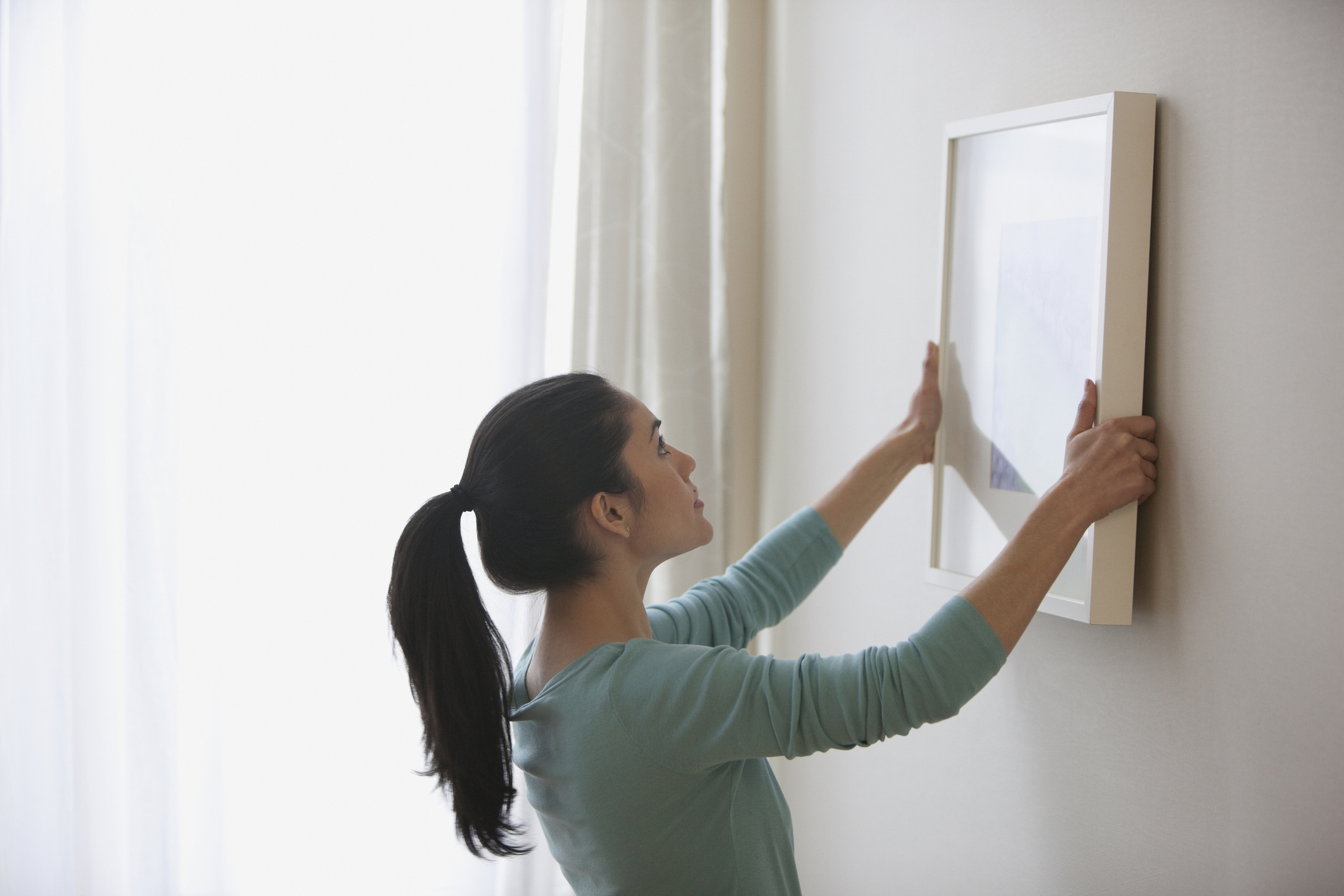 Woman hanging a frame on the wall