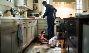 man cooking while children play on the floor