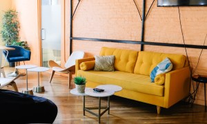 A living room with orange wall and yellow sofa