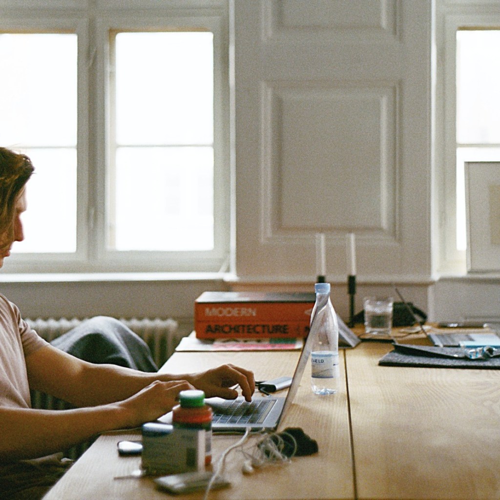 Man sitting at wooden table with laptop computer