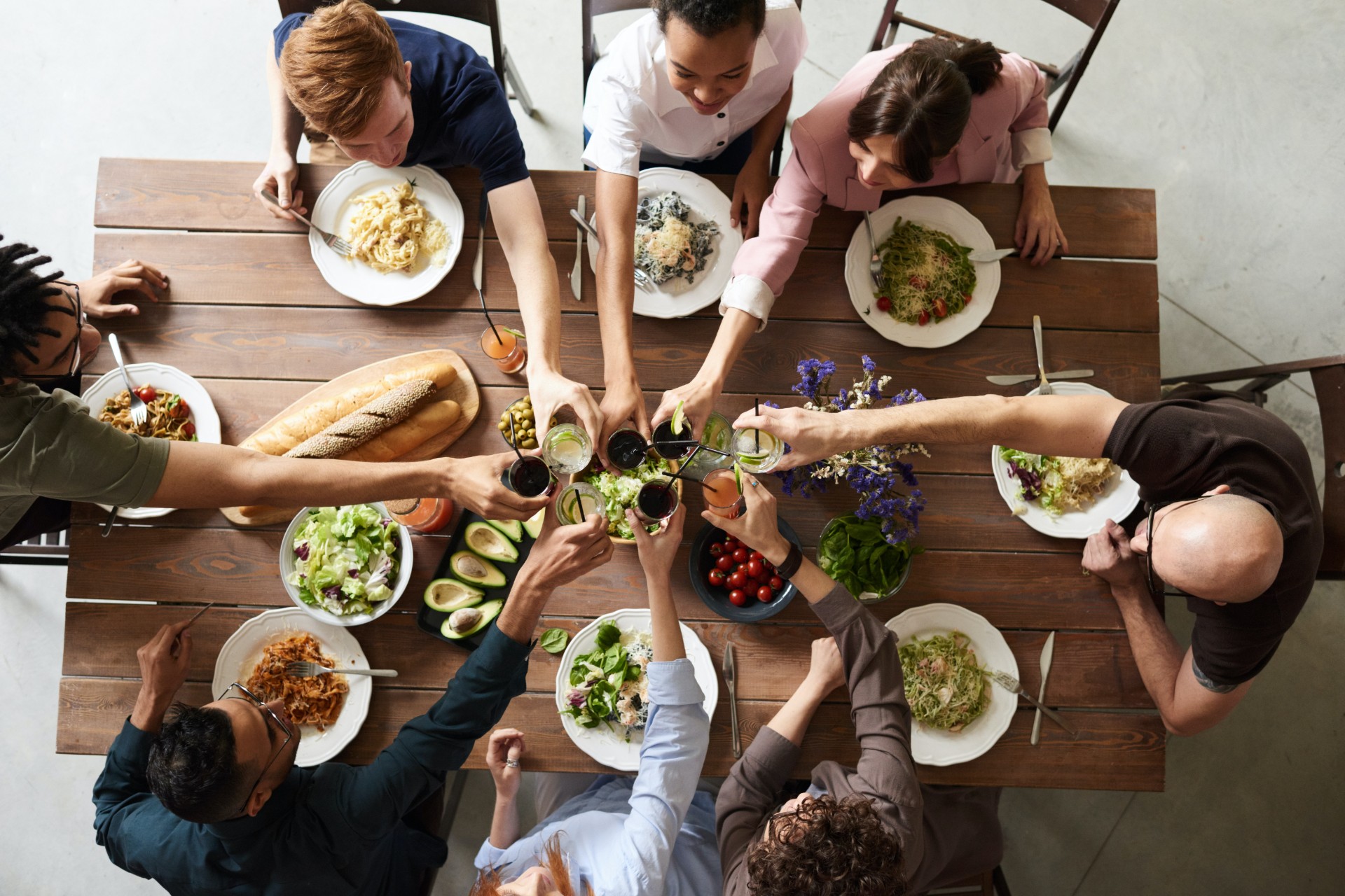 Friends sitting at wooden table eating dinner