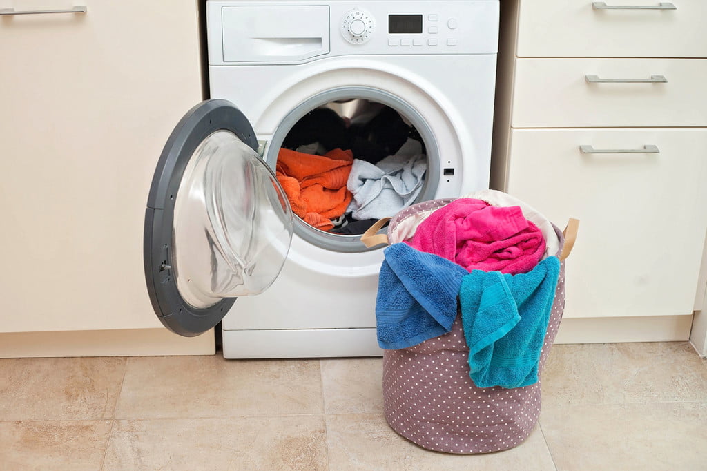 Laundry in wicker basket near washing machine