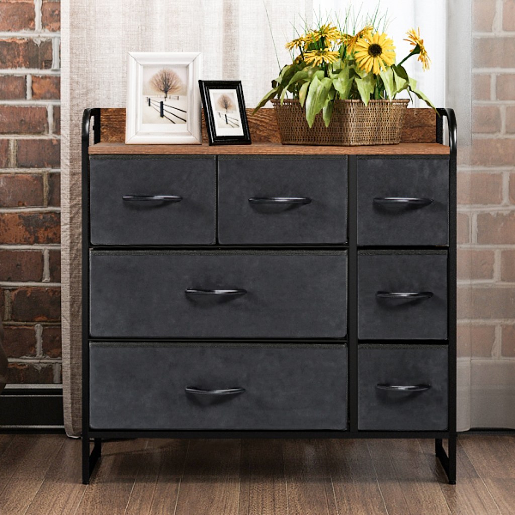 Black drawer unit with wooden top next to a bed