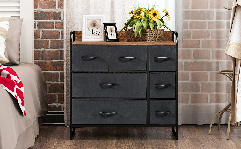 Black drawer unit with wooden top next to a bed