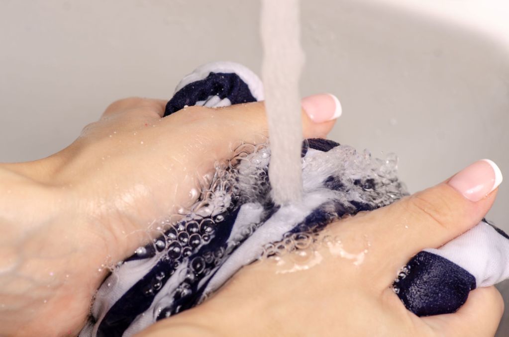 Female hands washing fabric under faucet