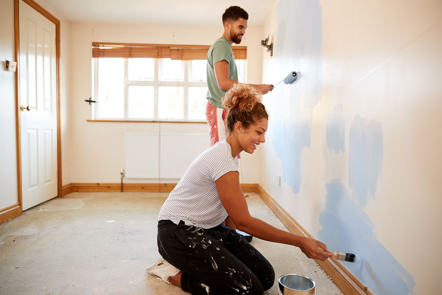 Two people painting an interior wall