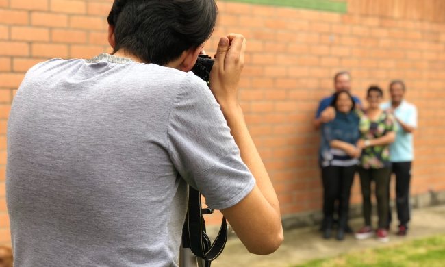 photographer taking a picture of a family by a brick wall