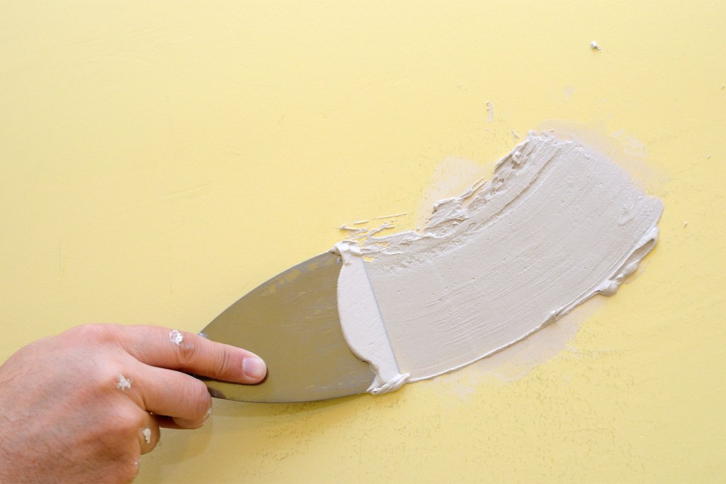 Person spackling yellow wall