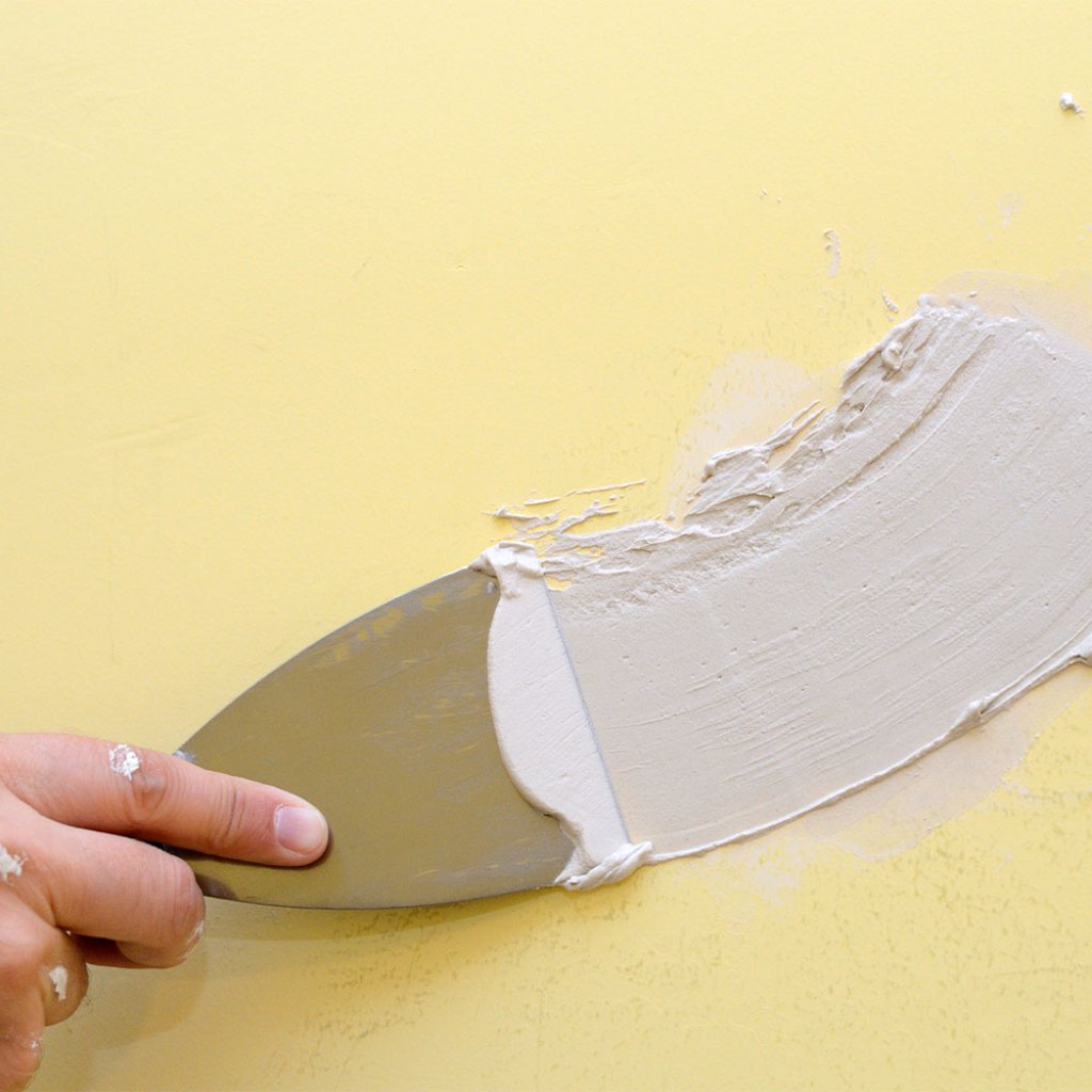 Person spackling yellow wall