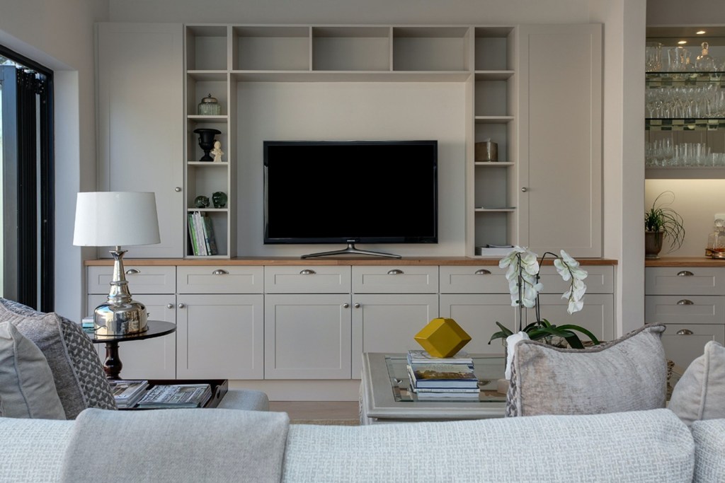 Living room in with furniture, shelves, and large TV