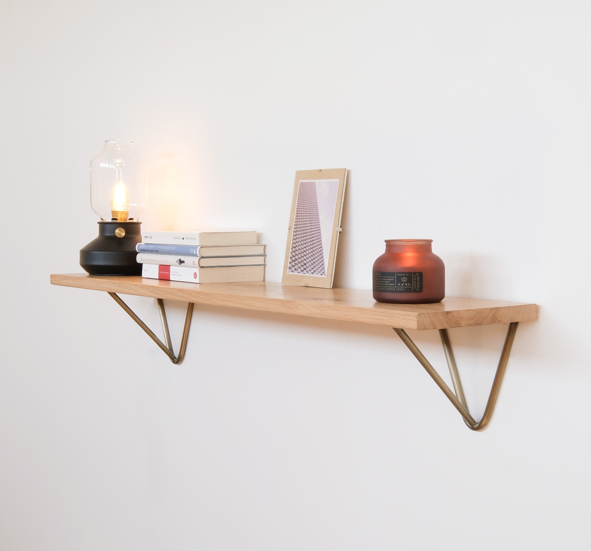 Wooden shelf with candles and other items on top.