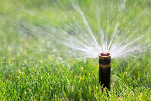 Close-up of sprinkler spraying water on grass