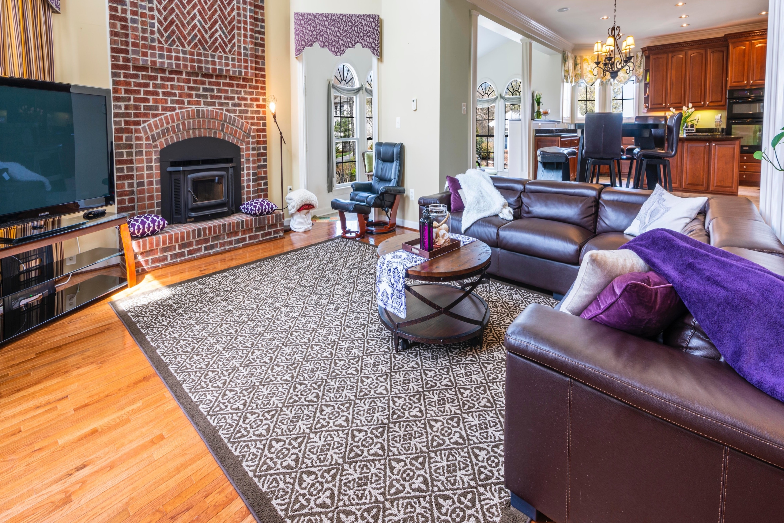 A dark rug on the floor of a light-colored living room.
