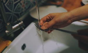 A close-up video of someone washing a fork in a sink.