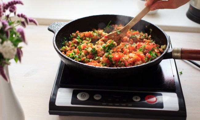 person stirring food in pan on portable cooktop