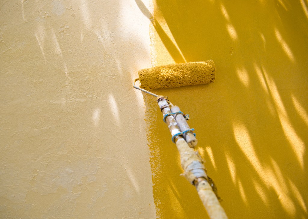 painting exterior wall yellow with a paint roller