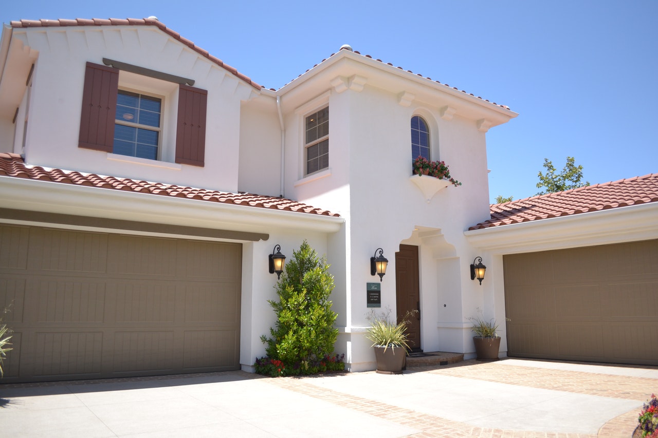 Two perpendicular garage doors on white two story home