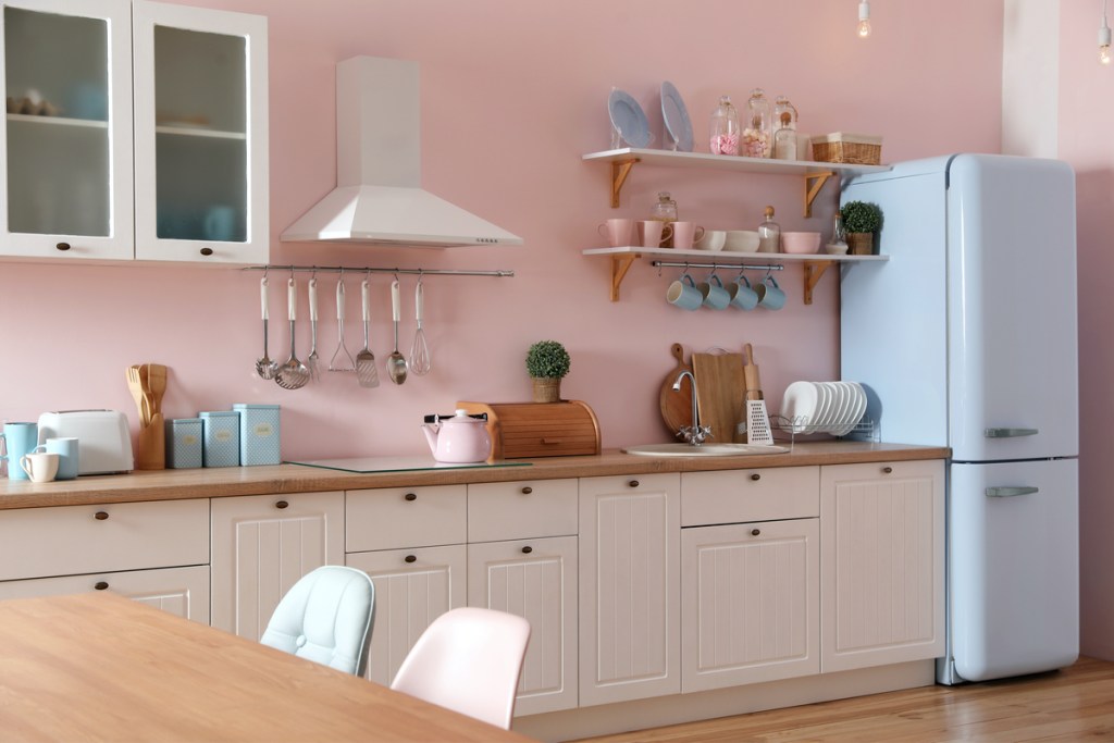 Stylish pink kitchen interior with dining table and chairs