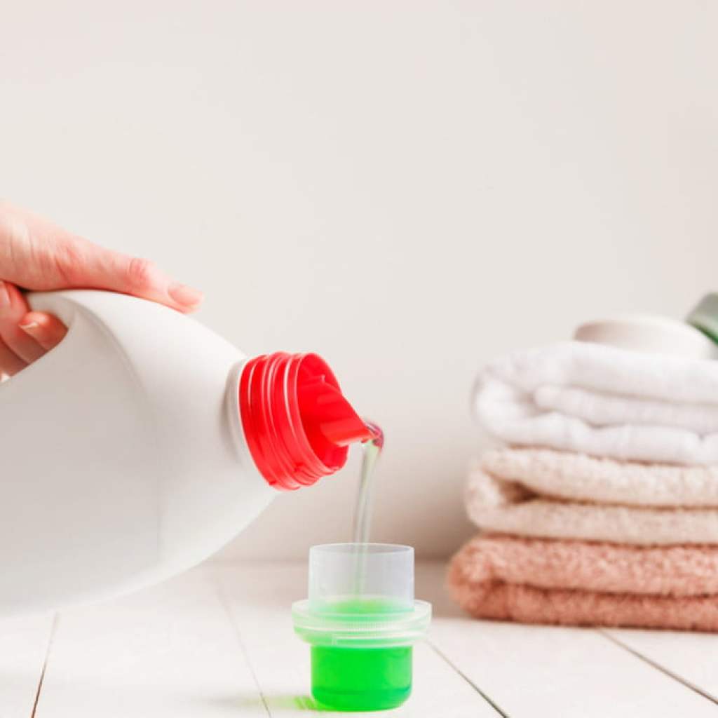 Lhand pouring liquid laundry detergent