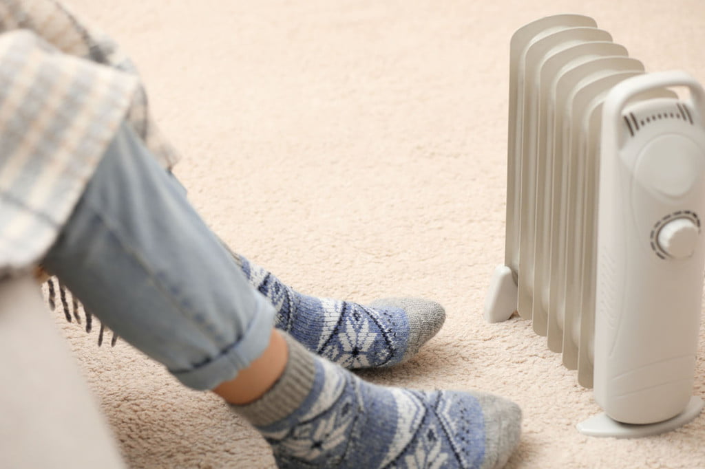someone wearing socks sitting next to a space heater