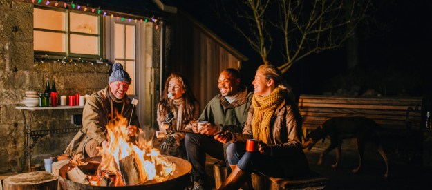 Two couples using a backyard firepit at night