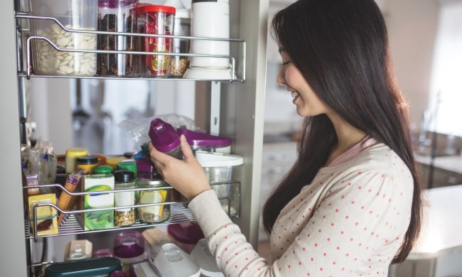 woman in kitchen taking spices from spice rack