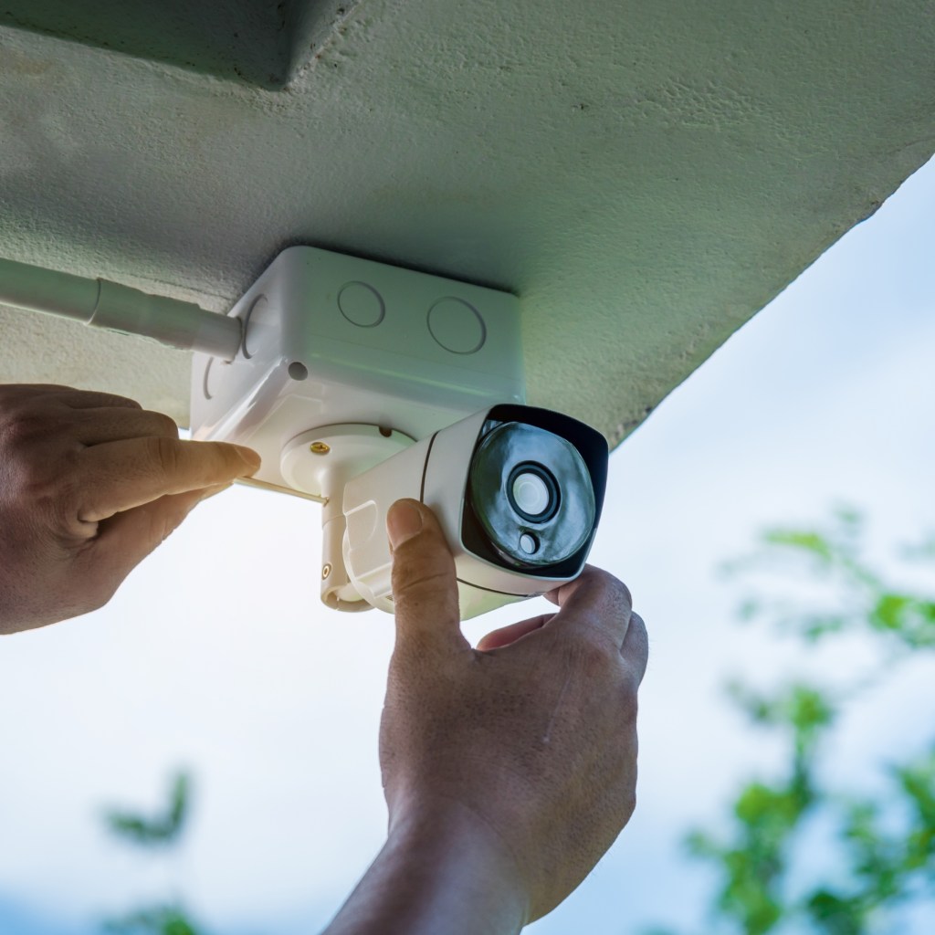 person installing wired home security camera