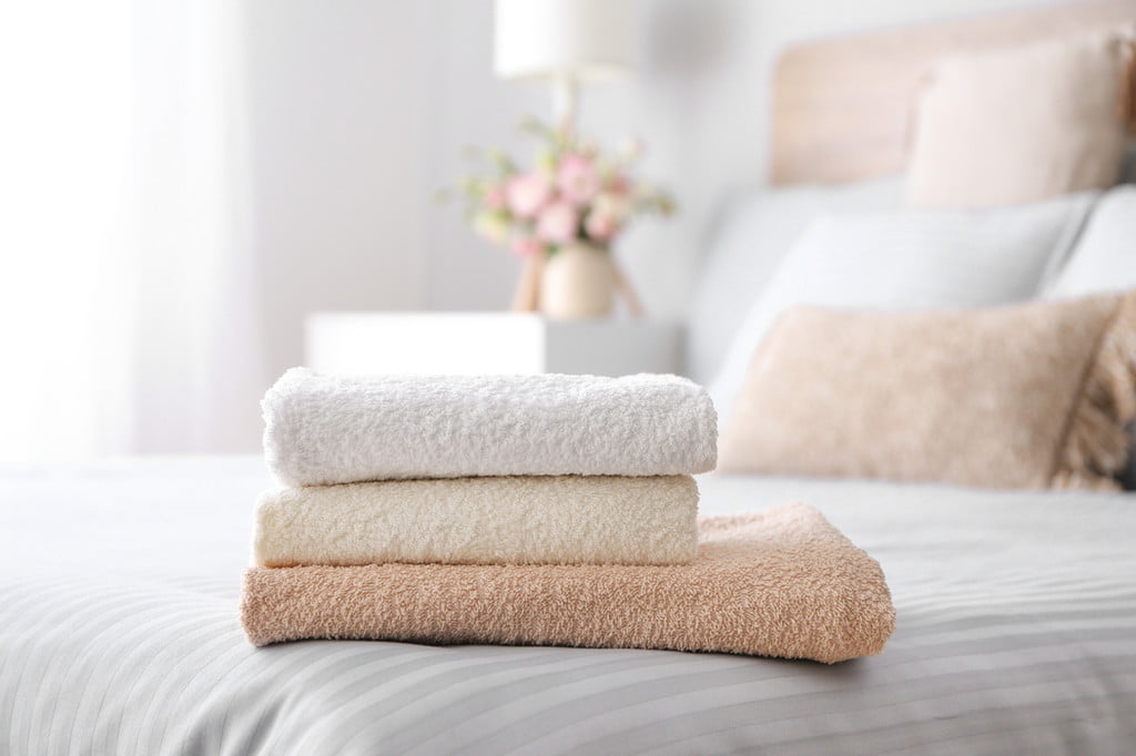 stack of bathroom towels on bed